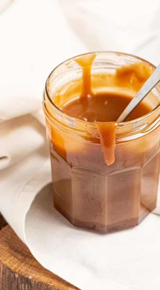 An open jar of Järna Buljong bone broth concentrate, glossy and amber, with a spoon resting inside